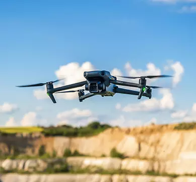 Un drone noir survolant un champ de terre.